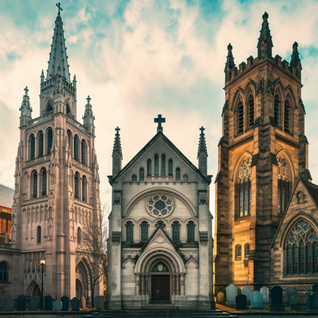 A picturesque, cinematic scene showcasing three of Pittsburgh’s most historic churches side by side: the grand Gothic spires of St. Paul Cathedral rising above a city skyline, the ornate façade of St. Anthony’s Chapel nestled in the Troy Hill neighborhood with hints of its vast relic collection inside, and the sandstone Gothic exterior of Trinity Cathedral downtown, surrounded by historic gravestones. The sky is bright with soft golden-hour lighting, illuminating the stained glass windows. The overall tone is warm, reverent, and timeless—celebrating Pittsburgh’s architectural and cultural heritage.