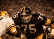 A Pittsburgh Steelers defensive lineman in the classic 1970s black and gold uniform breaks through an offensive line under stadium lights, capturing the intensity of the Steel Curtain defense.
